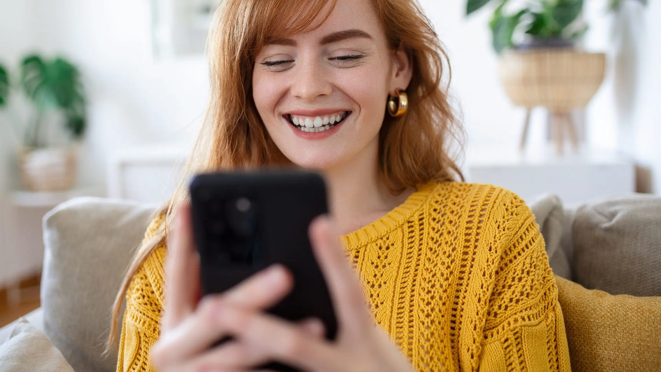 Eine junge Frau lacht und schaut auf ihr Handy