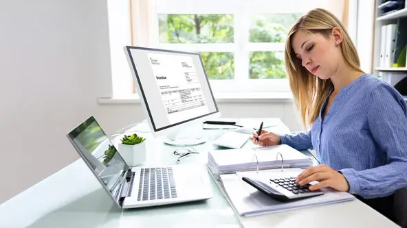 Frau sitzt am Schreibtisch in einem Büro vor einem Aktenordner