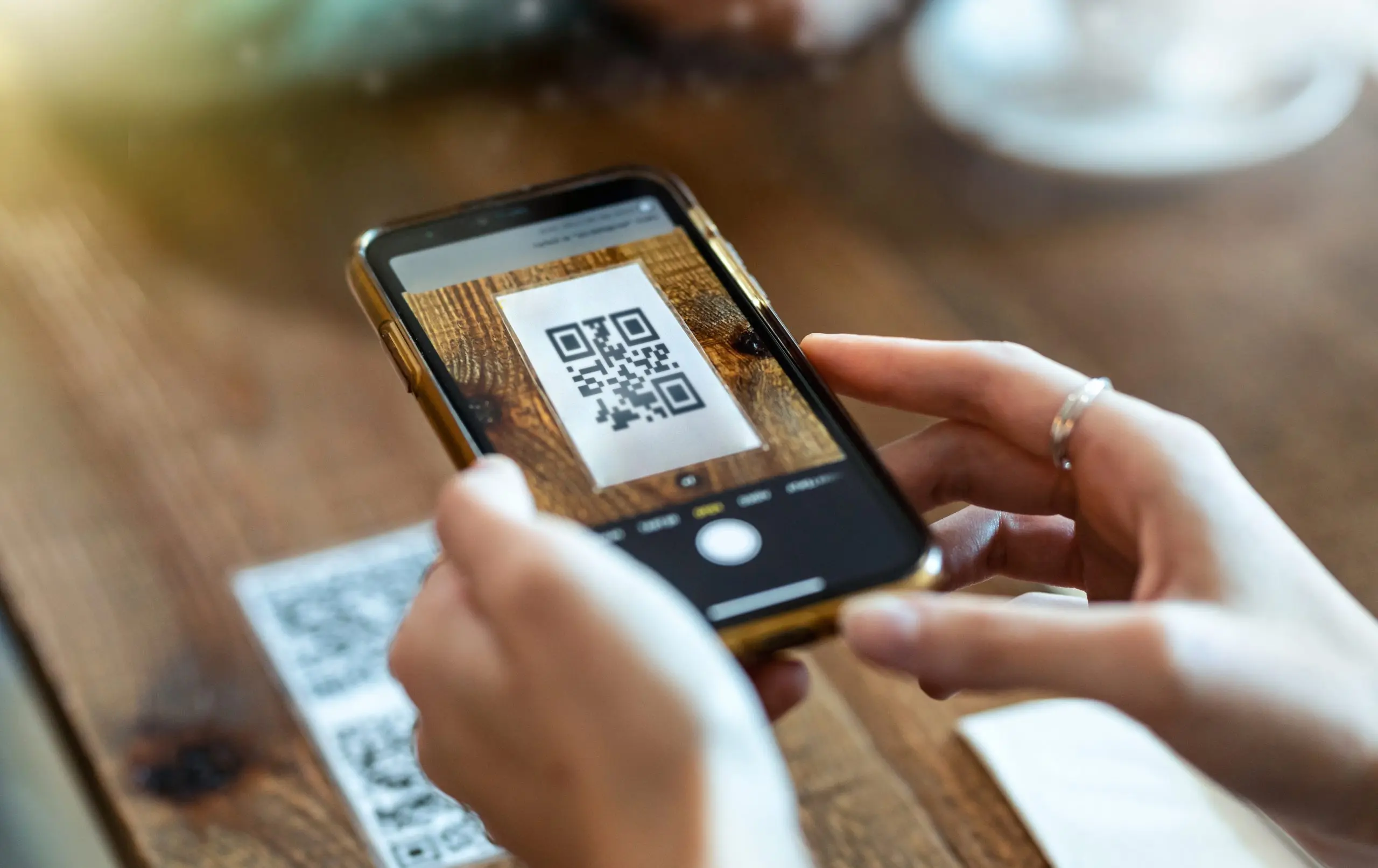 Frau hält Smartphone Kamera auf einen QR-Code und scannt diesen.