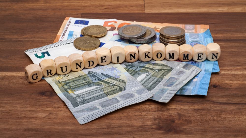 Geldscheine und Münzen, auf denen Holzwürfel mit dem Text 