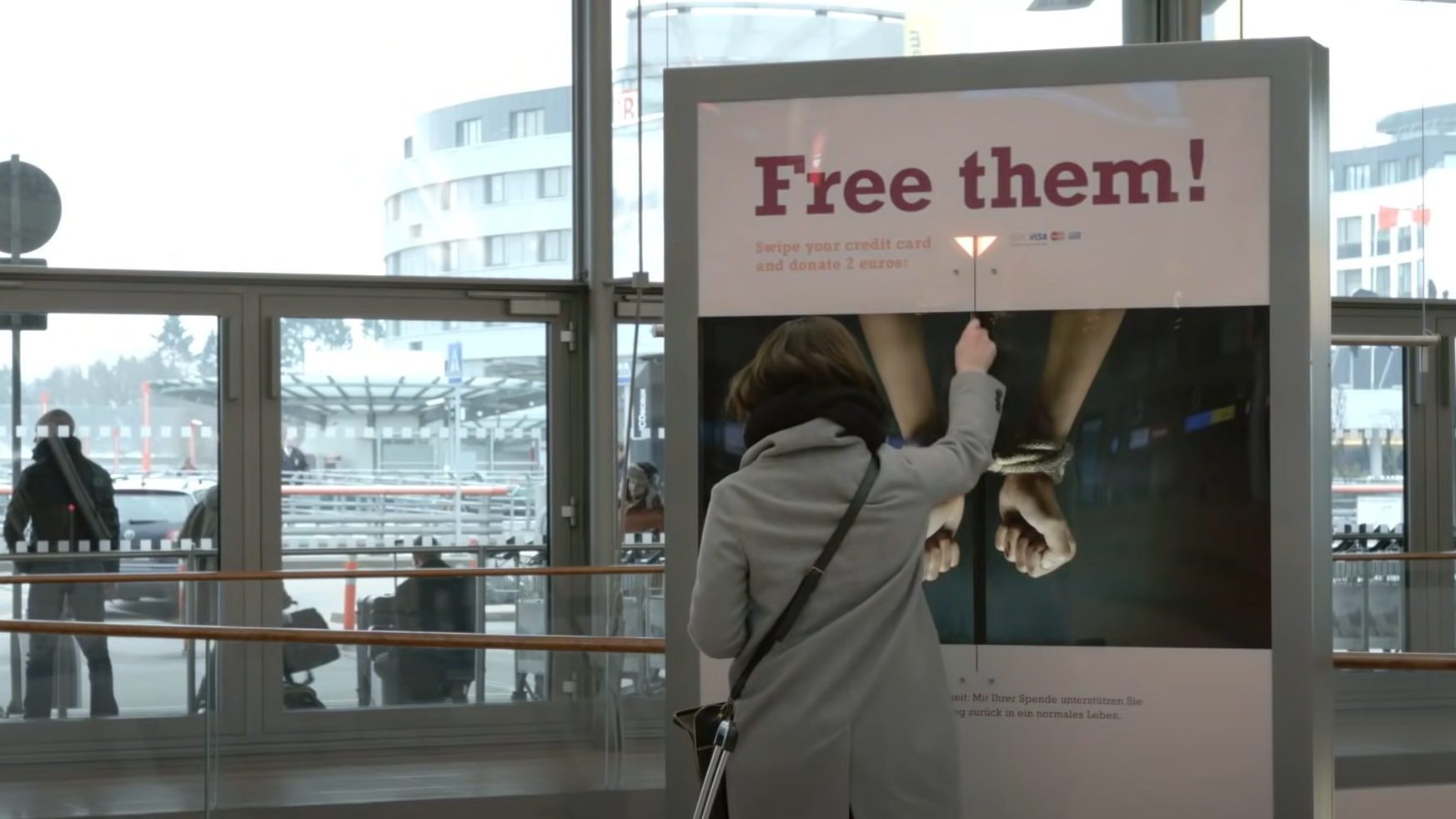 Eine Frau steht vor einer Säule und hält ihre Karte hin. Auf der Säule steht 
