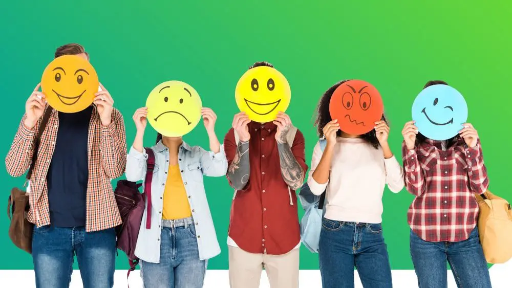 Ein Gruppe Menschen hält Smiley mit verschiedenen Gesichtsausdrücken vor das Gesicht